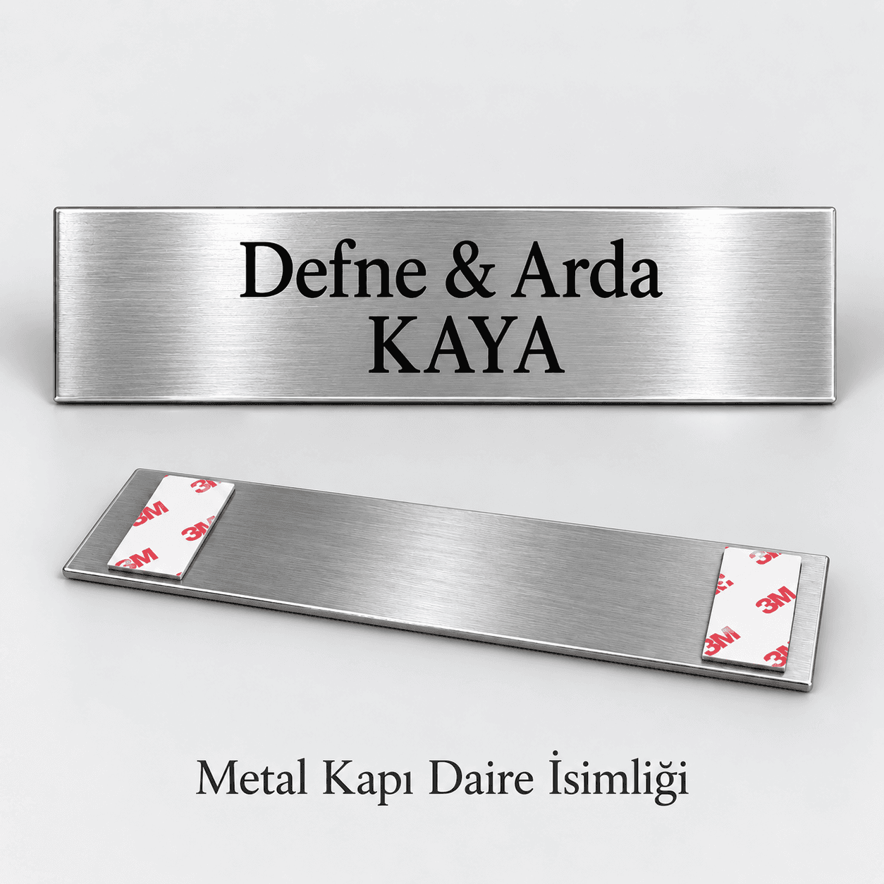 İki isim ve soyadı yazılı gümüş rengi fırçalı metal kapı isimliği, arkasında yapışkan bant